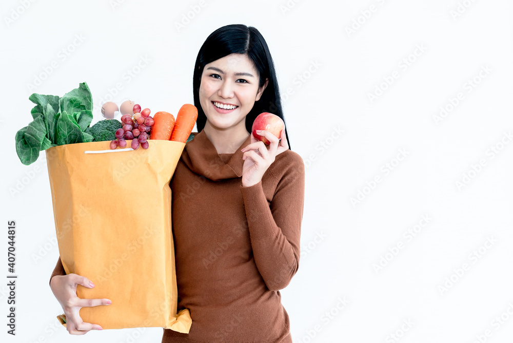 Portrait images of Asian attractive Woman holding paper bag which contains food and fresh vegetables On white background, to people shopping online concept. Portrait images of Asian attractive Woman holding paper bag which contains food and fresh vegetables On white background, to people shopping online concept.