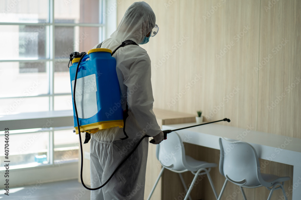Health care worker in PPE protective suit spraying to disinfect the virus pandemic in the office Health care worker in PPE protective suit spraying to disinfect the virus pandemic in the office