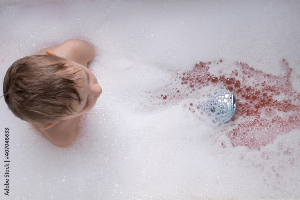 The child makes lather in the bath with the shower. Red water. The child makes lather in the bath with the shower. Red water.