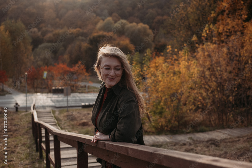 Fototapeta premium Young beautiful woman having a walk outdoors on golden our autumn. Lifestyle concept