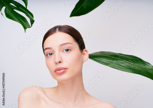 Portrait of a delightful young beauty with green tropical leaves.