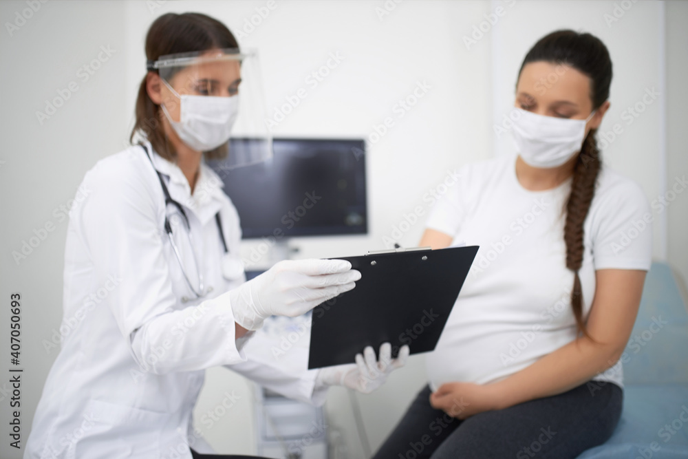 Pregnant woman wearing mask during visit at medical center Pregnant woman wearing mask during visit at medical center