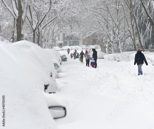 Pedestrians walking with great difficulty on a street completely covered with snow