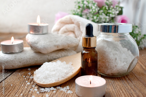 Aromatherapy concept with essential oil bottle, sea salt, burning candles and pebbles. Spa or herbal medicine still life composition. Copyspace.