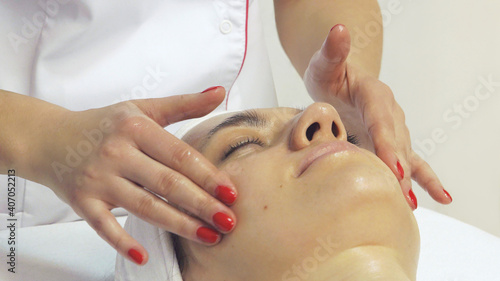 Portrait of beautiful young woman enjoying face massage, close up