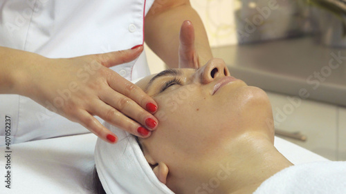 Portrait of beautiful young woman enjoying face massage, close up