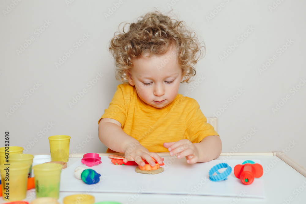 Cute Caucasian blond curly baby boy child playing with sensor kinetic toy playdough. Hand brain development activity for young toddlers kids. Early age preschool education. Cute Caucasian blond curly baby boy child playing with sensor kinetic toy playdough. Hand brain development activity for young toddlers kids. Early age preschool education.