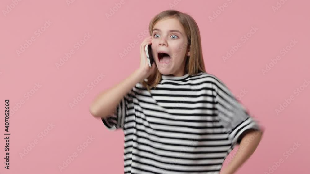 Amazed overjoyed little kid girl 12-13 years old in white black basic striped t-shirt isolated on pink background studio. Childhood lifestyle concept. Talking on mobile cell phone doing winner gesture Amazed overjoyed little kid girl 12-13 years old in white black basic striped t-shirt isolated on pink background studio. Childhood lifestyle concept. Talking on mobile cell phone doing winner gesture