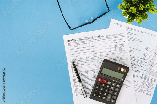 Tax Form 1040 and Calculator on Light Blue Background
