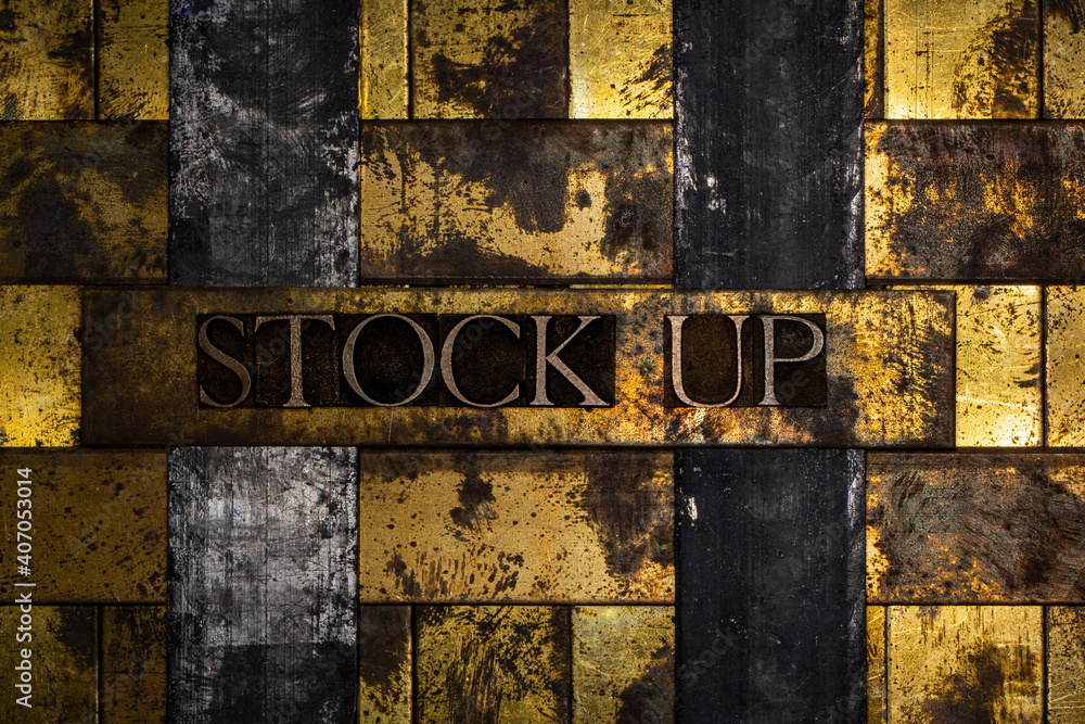 Stock Up text formed with real authentic typeset letters on vintage textured silver grunge copper and gold background