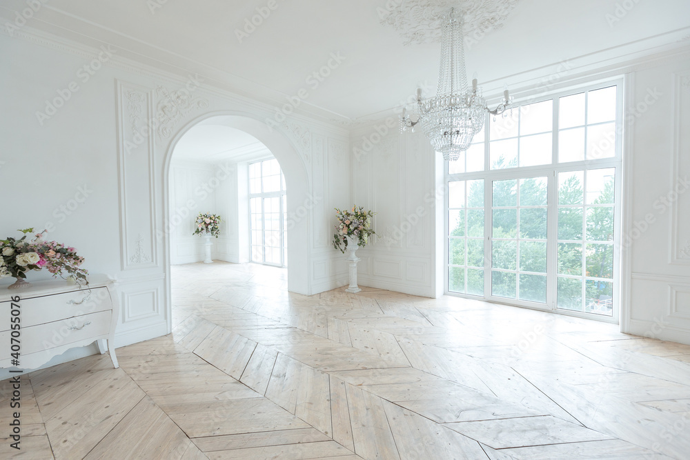 chic white huge spacious hall with a minimum of expensive antique furniture. Baroque interior design with ornament on the walls and parquet on the floor. chic white huge spacious hall with a minimum of expensive antique furniture. Baroque interior design with ornament on the walls and parquet on the floor.