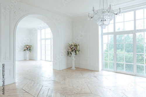 chic white huge spacious hall with a minimum of expensive antique furniture. Baroque interior design with ornament on the walls and parquet on the floor.