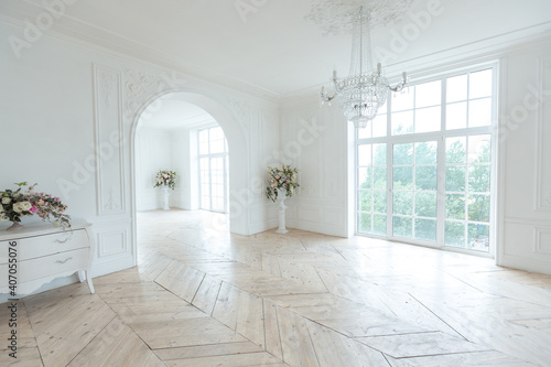 chic white huge spacious hall with a minimum of expensive antique furniture. Baroque interior design with ornament on the walls and parquet on the floor.