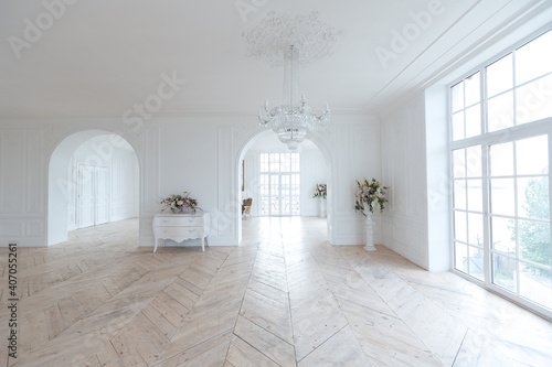 chic white huge spacious hall with a minimum of expensive antique furniture. Baroque interior design with ornament on the walls and parquet on the floor.