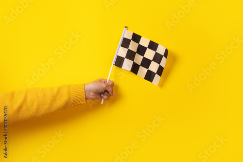 checkered flag in hand over yellow background photo