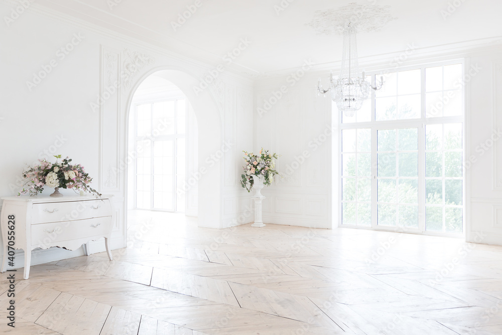 chic white huge spacious hall with a minimum of expensive antique furniture. Baroque interior design with ornament on the walls and parquet on the floor.