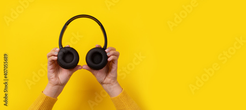 black headphones in hand on yellow background