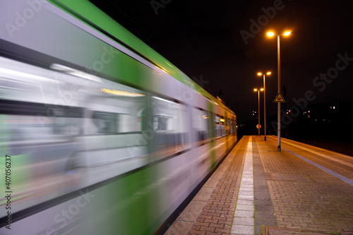Night outdoor scenery of platform railway station and regional train with blur motion.