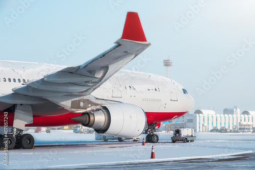 Winter scene of the airport. Modern twin-engine cargo airplane stand at apron ready for cargo load. Snow over fuselage of cargo airplane.