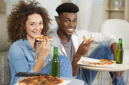 portrait of a young couple eating pizza at home