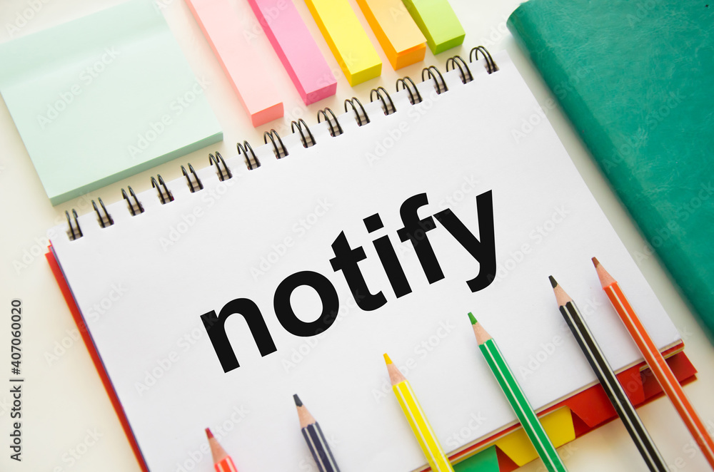 the word notify is written on a white notepad which lies on a white background near a green notepad and stickers the word notify is written on a white notepad which lies on a white background near a green notepad and stickers