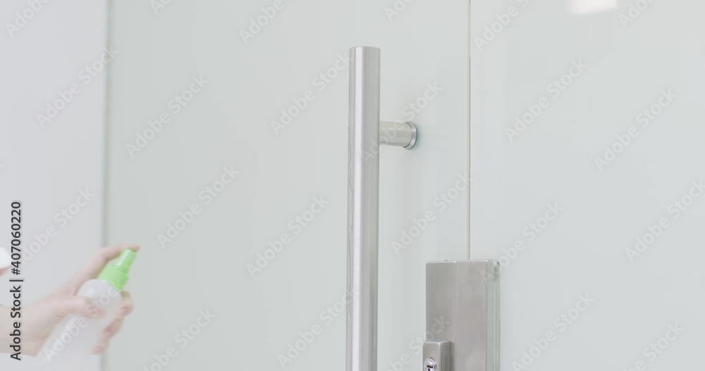 Womans hand clean door handle by sanitizer spray and wipe. Office cleaning service during coronavirus pandemic, close up Womans hand clean door handle by sanitizer spray and wipe. Office cleaning service during coronavirus pandemic, close up
