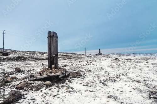 A broken telegraph pole on a snow-covered Arctic hill. Minimalistic polar landscape.