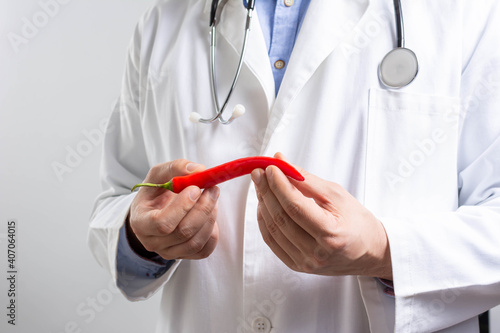 Doctor Hands holding red hot chilli peppers vegetables. closeup mexican chilli pepper in doctor hands over a grey background. photo