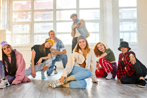 Obraz na plátně woman in casual wear with colleagues dancers posing at camera in studio, sit on the floor looking at camera