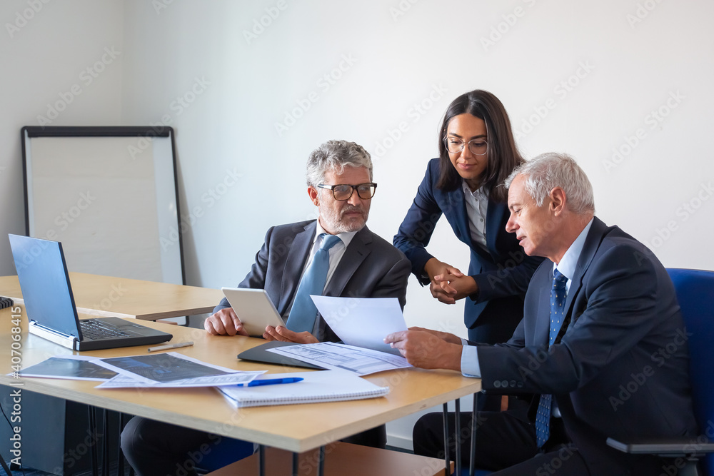 custom made wallpaper toronto digitalSerious colleagues reading document and working with statistics. Professional content businesspeople in office suits sitting at table with laptop, papers and tablet. Management and partnership concept