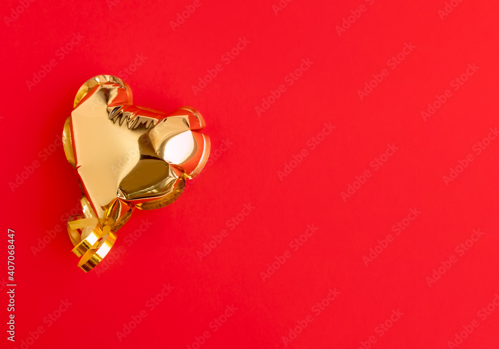 Gold balloon in the shape of a heart on a red background with space for ...