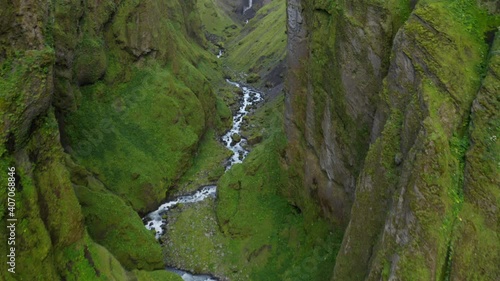 Smooth Drone footage flying through deep Icelandic Mulagljufur canyon, with dramatic Hangandifoss waterfall at the end of the canyon, in Southern Region, Iceland photo