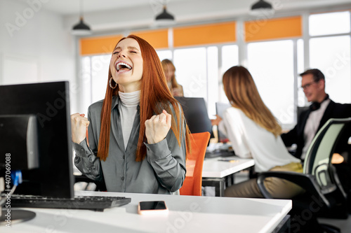 female office worker woman has wow reaction sitting at office desk and looking at computer screen, she is happy surprised excited receive good online results