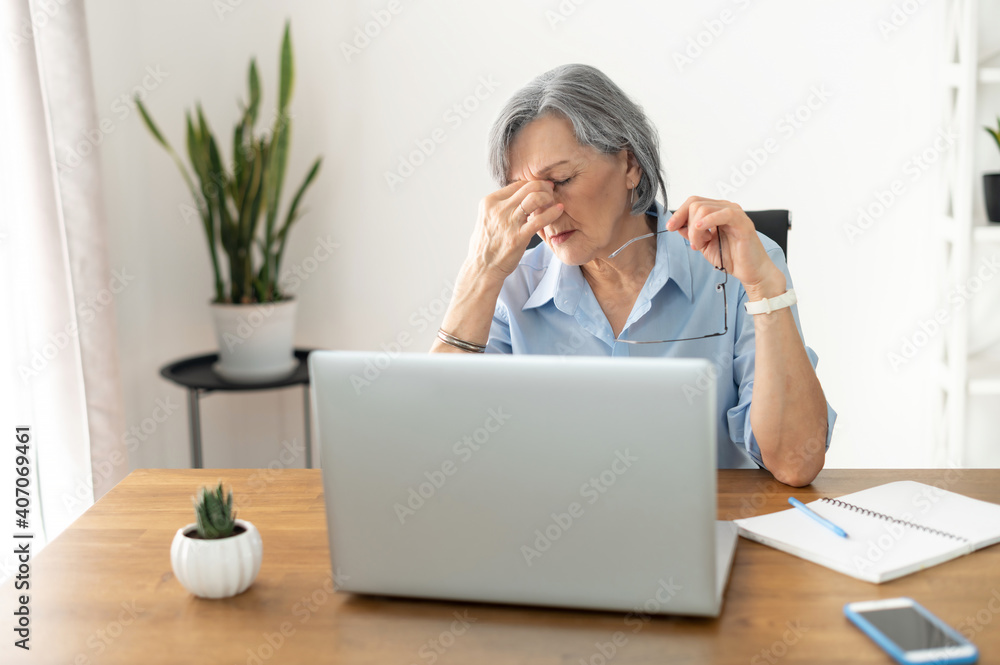 Tired and overworked stressed mature woman working on laptop at home indoor, female teacher feeling exhausted after lecturing students online, touching eyes. Smart working senior people and technology Tired and overworked stressed mature woman working on laptop at home indoor, female teacher feeling exhausted after lecturing students online, touching eyes. Smart working senior people and technology