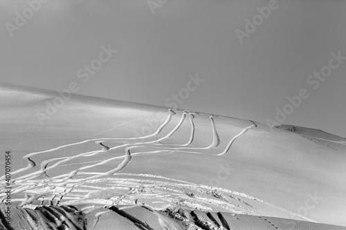 Snowy off-piste ski slope with trace from skis and snowboards at winter night