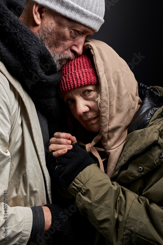 two beggars, homeless people support each other try to warm up, in dirty wear, hugging. poverty concept