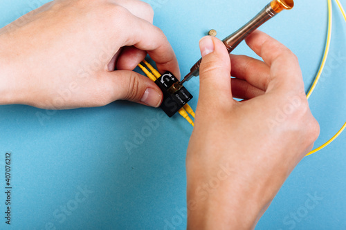 Women Handholds a screwdriver for tuning the optic attenuator. Selective focus. Blue background photo