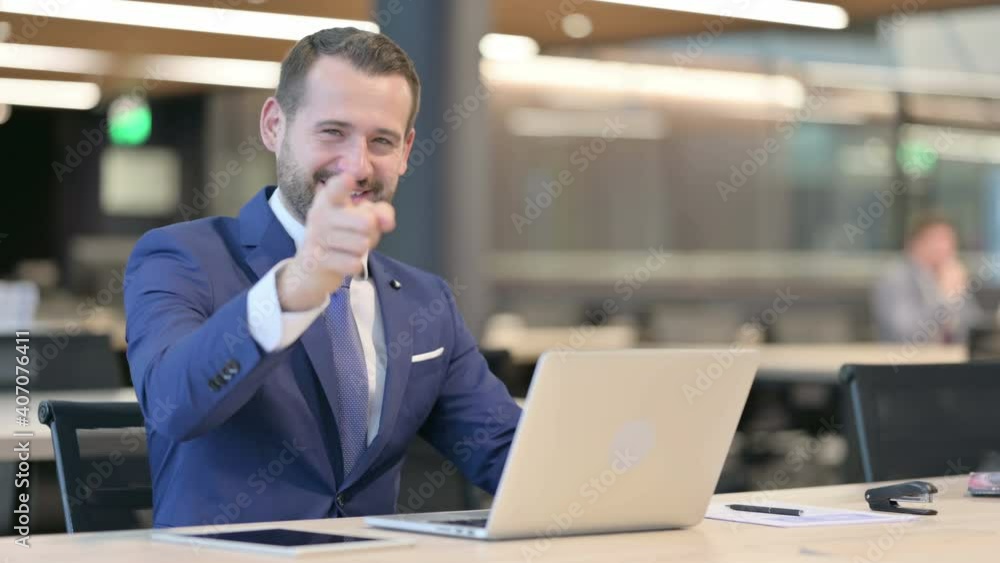 Middle Aged Businessman with Laptop Pointing at Camera Middle Aged Businessman with Laptop Pointing at Camera
