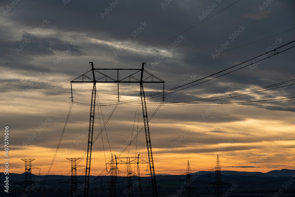 Electric poles in a field during the sunset