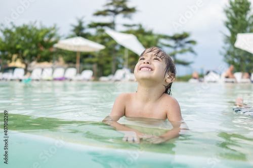 Cute little boy kid child splashing in swimming pool having fun leisure activity