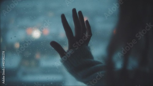 Hand of a woman touching a window in a rainy day