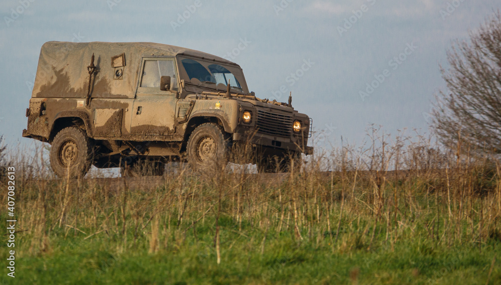 mud covered army land rover defender 4x4 driving along a track mud covered army land rover defender 4x4 driving along a track