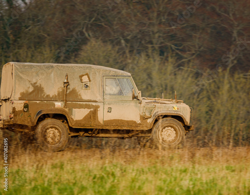mud covered army land rover defender 4x4 driving along a track