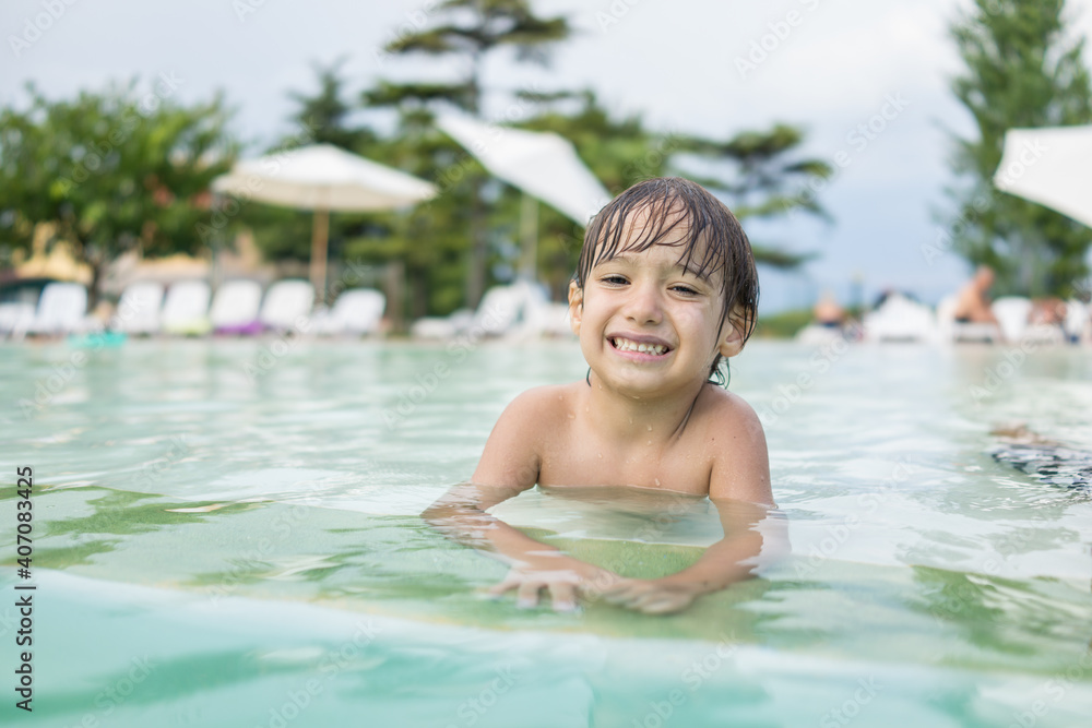 Cute little boy kid child splashing in swimming pool having fun leisure activity