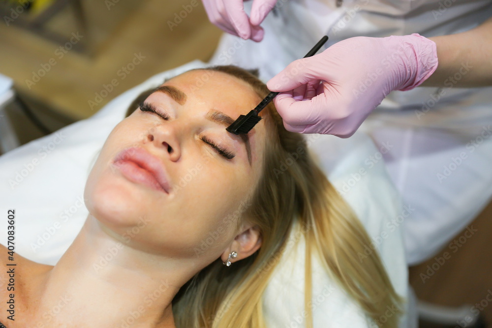 Naklejka premium beautician makes eyebrow care for woman. eyebrow brushing close up