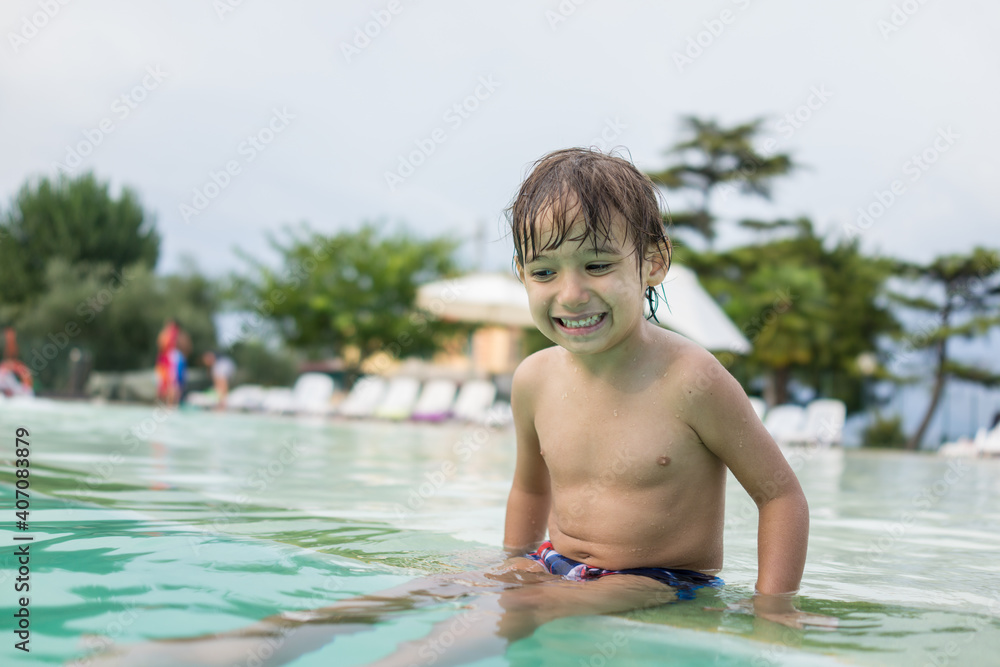 Young boy kid child splashing in swimming pool having fun leisure activity