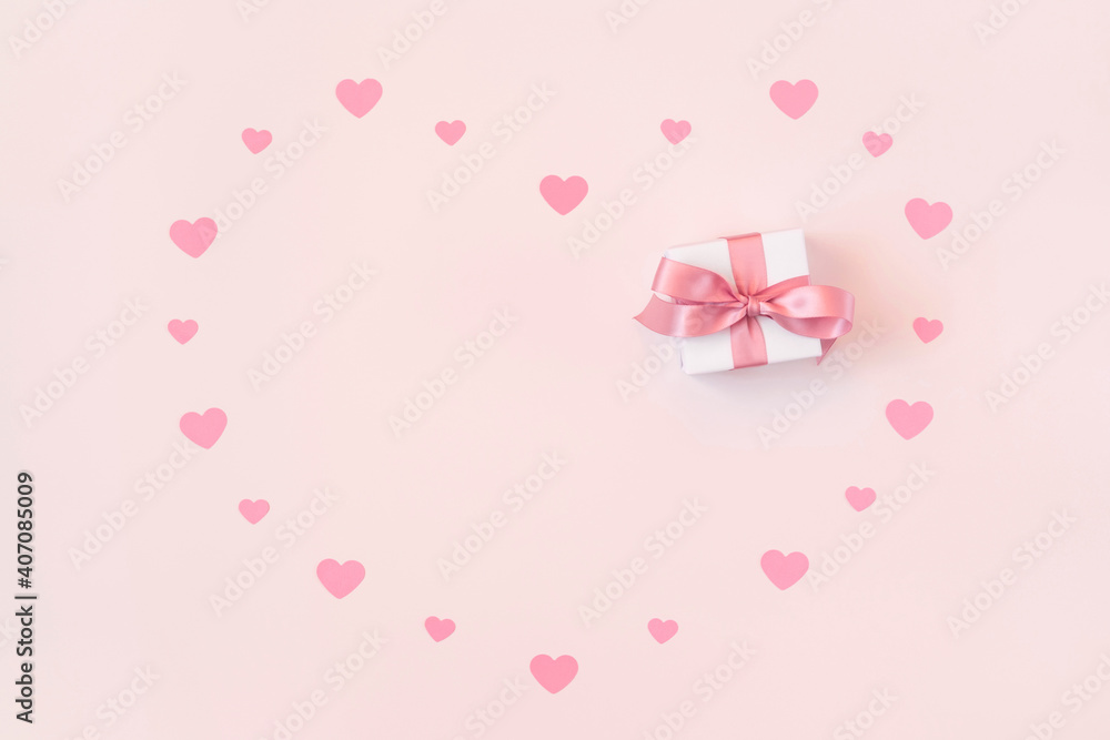 Greeting card for Valentine's Day. Small confetti hearts and a gift on a pink background. Valentines day concept. Space for text.
