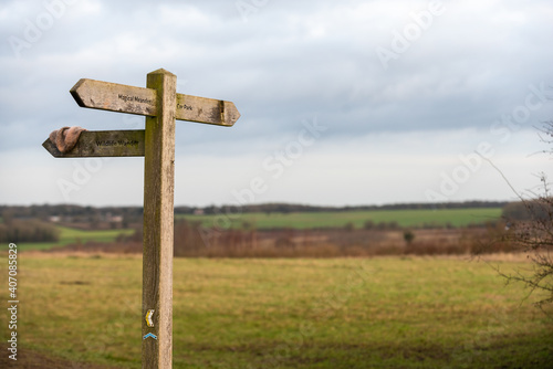 Wooden signpost outside on a public footpath through countryside with a lost item of clothing