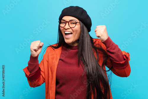 latin woman feeling happy, positive and successful, celebrating victory, achievements or good luck