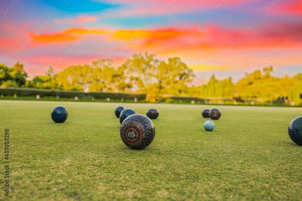 Lawn bowls balls in a field after the game with a colourful sunset